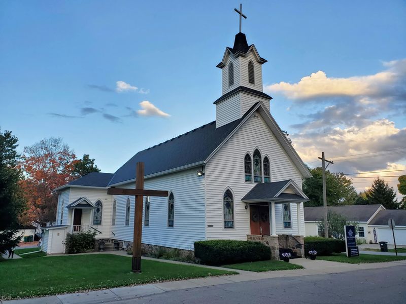 Church exterior and wooden cross at sunset in the fall