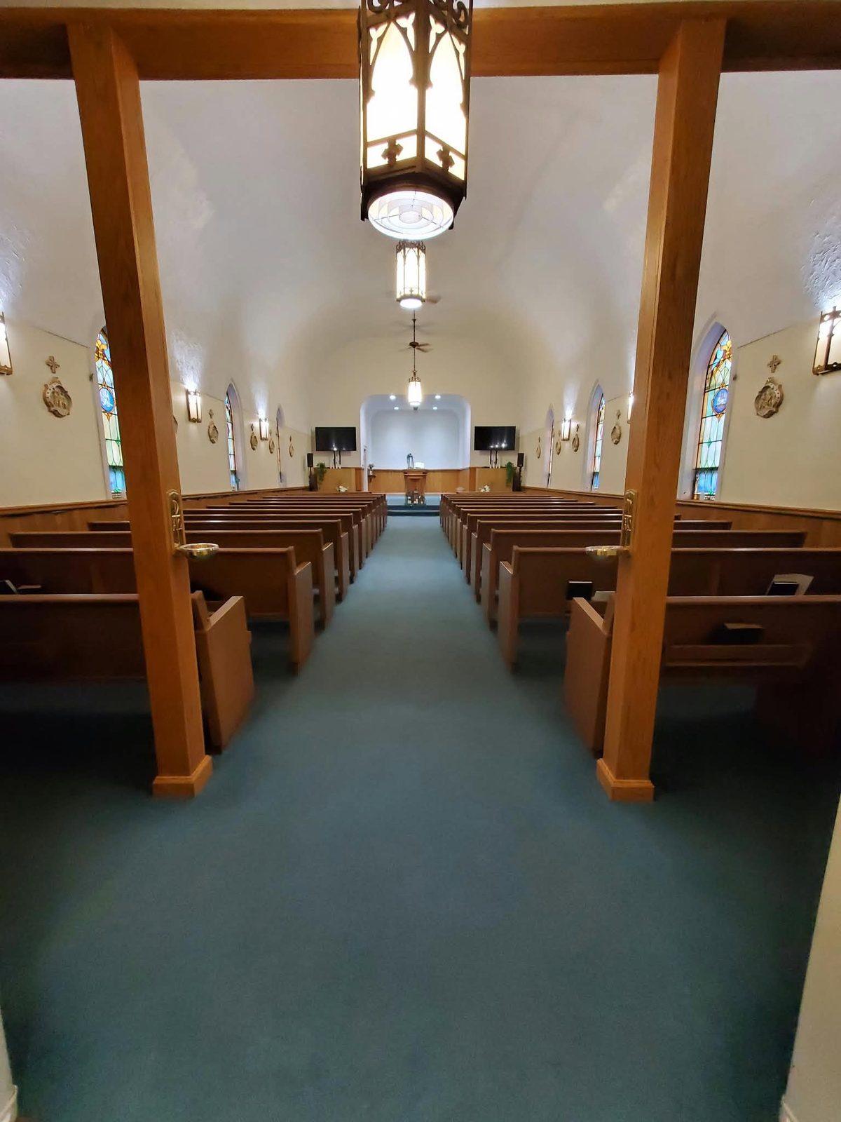 Sanctuary aisle and pews seen from the back between wooden posts
